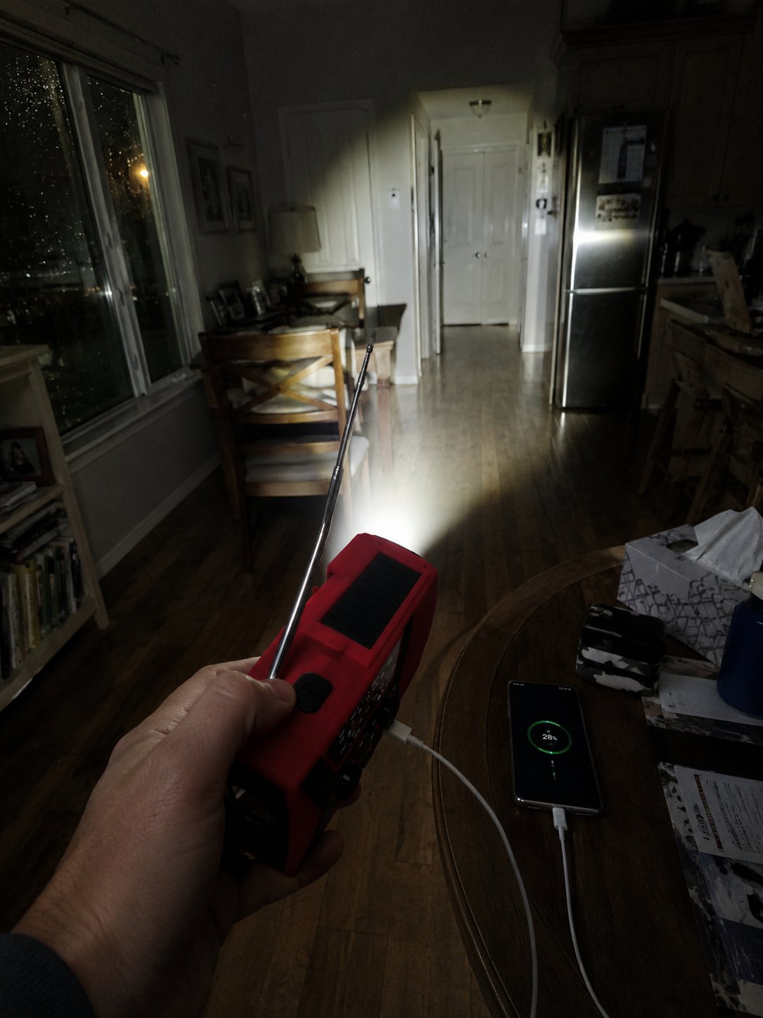 The red RELVIE-R1 held in one hand, antenna up, flashlight on